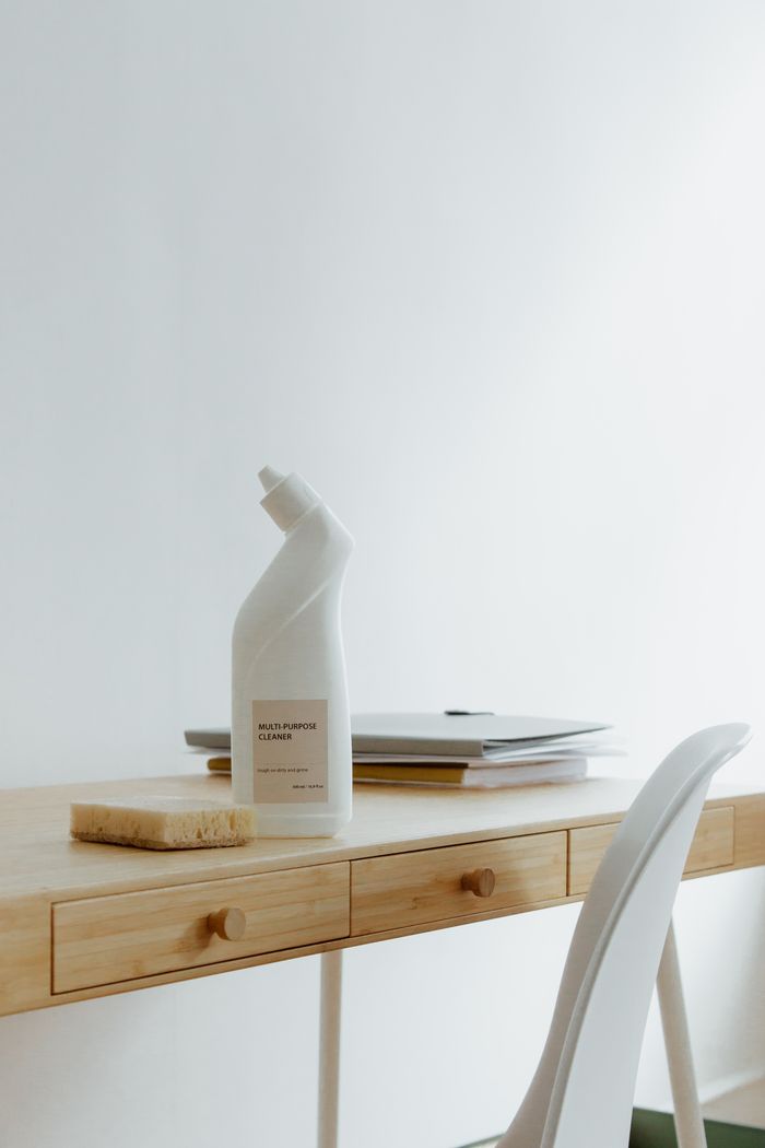 about-us-01 A clean and organized home office desk with a cleaner bottle and sponge, emphasizing simplicity and functionality.